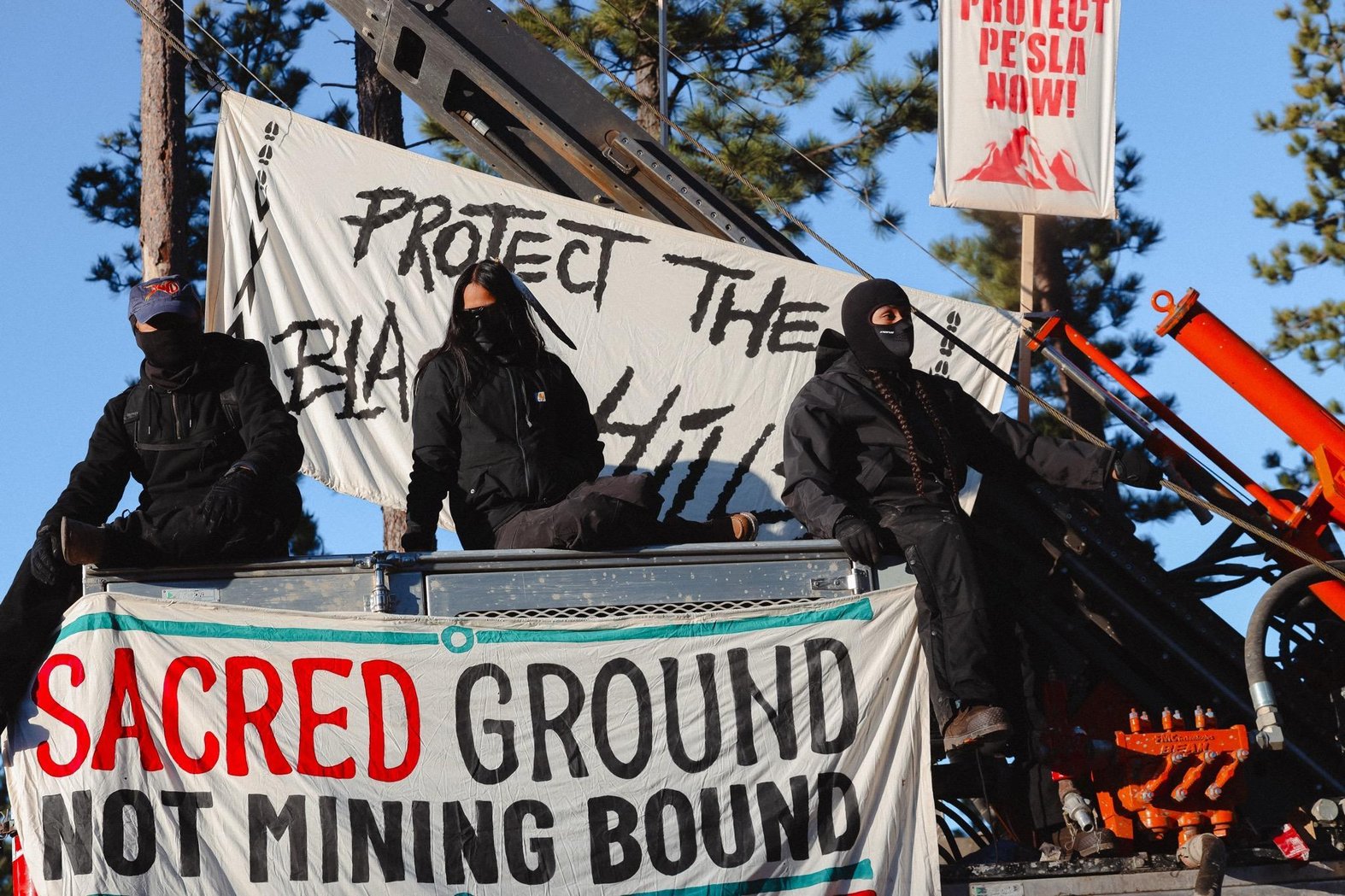 Demonstrators lock themselves to construction equipment in April 2026 at a planned mining site near Pe’Sla, a culturally important part of the Black Hills that NDN Collective has fought to protect. Credit: Angel White Eyes.