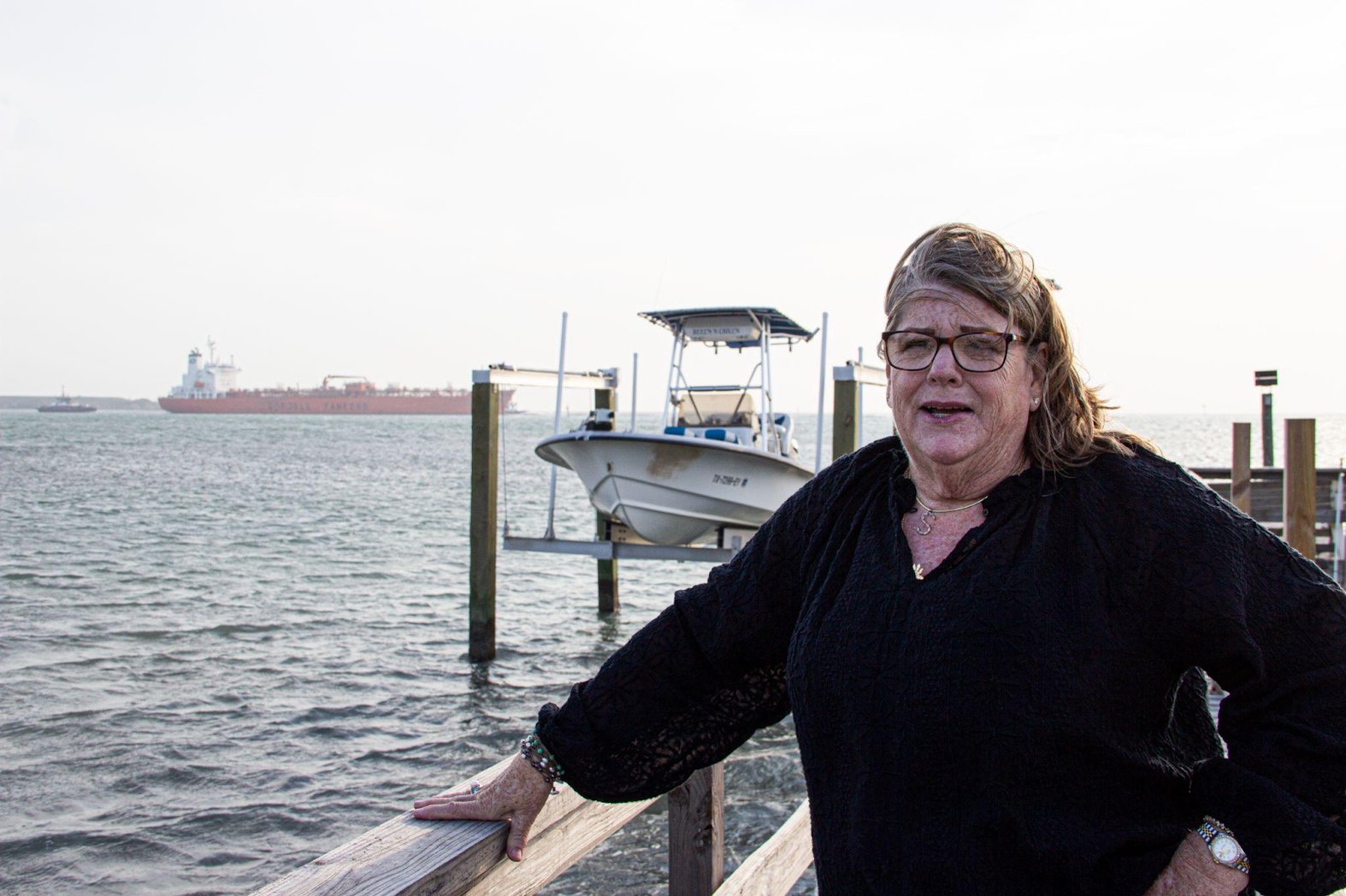 Suzi Wilder describes how the environs surrounding her jetty at Ingleside on the Bay, Texas, have changed, as an oil tanker passes behind her. (Alex Ip/The Xylom)