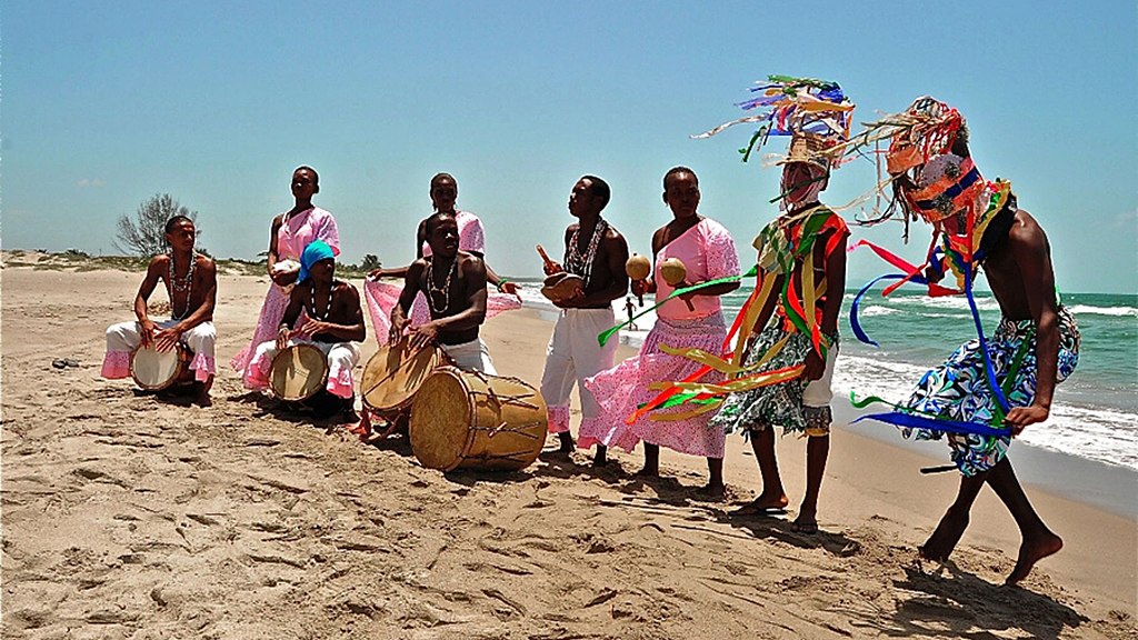 A group of Garifunas performing a Punta demonstration at the beach. Photo by Alvaro Dia, via Wikimedia Commons.